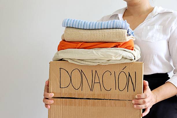 istock Woman holding cardboard box with second hand clothes and 
