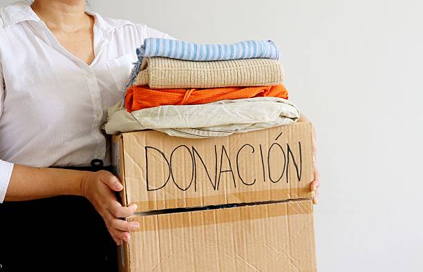 istock Woman holding cardboard box with second hand clothes and 