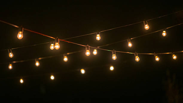 istock String of warm glowing light bulbs hanging in dark night.. 2248936004