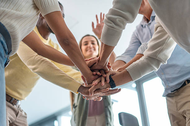 istock Overhead View of Enthusiastic Executives Joining Hands in Office 2248939180