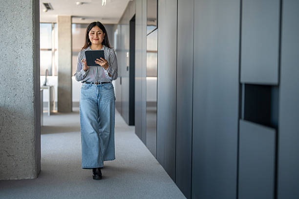 istock Hispanic Woman Confidently Walking with Tablet in Modern Office 2248940792