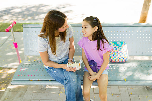 istock Mother and daughter sharing a meal and bonding while sitting on a park bench, enjoying their time together outdoors 2248941380