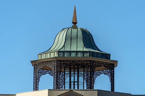 A green gazebo with intricate black wrought iron detailing