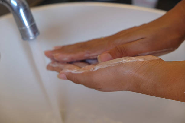 Close-up shot of hands covered with soap under a running faucet in a bathroom sink.Concept:hand washing, hygiene, cleaning hands, running water, soap, health, safety, bathroom sink, prevention, virus protection, washing hands close up