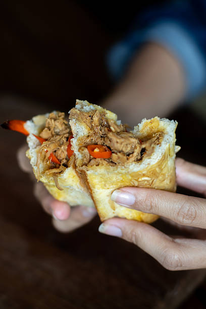 istock Close-up of hands breaking open a stuffed bread roll with savory shredded filling 2248949137