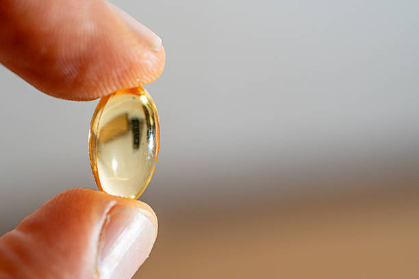 istock Omega-3 capsule tablet placed between the thumb and index finger. 2248950948