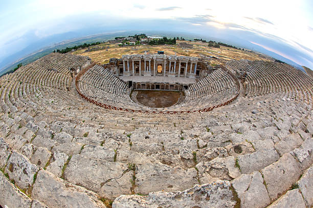 Visitors can explore the ancient amphitheater in Hierapolis, Turkey, marveling at its impressive architecture and historic significance while enjoying a beautiful sunset over the landscape.
