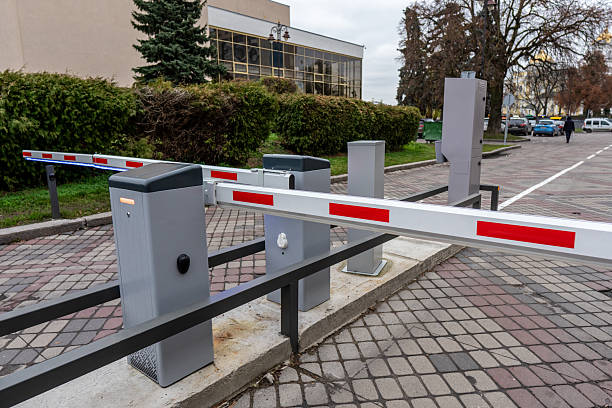istock A security boom barrier with red stripes is completely lowered, blocking access to a paved road near a modern building. 2248958089