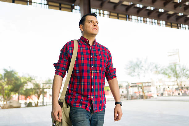 istock Man walking outdoors, carrying bag, looking up with determined expression, navigating urban environment 2248958134
