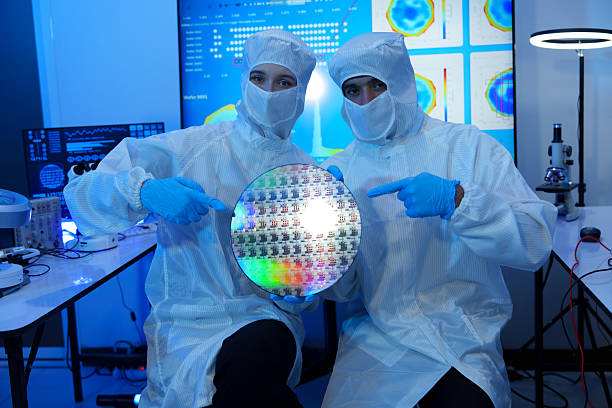 istock Engineers in sterile suits work at a semiconductor manufacturing plant using microscopes in a lab. 2248959673