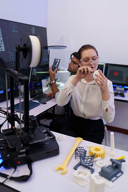 istock Engineers work with a 3D printer to print a clear white plastic model. State-of-the-art technology, selective focus, in a lab. 2248959716