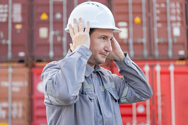 istock Industrial worker adjusting safety helmet at cargo container yard, Logistics engineer preparing for inspection at shipping depot, Warehouse technician wearing hard hat for safety compliance 2248965137