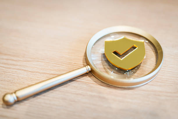 istock Magnifying glass focusing on golden shield with check mark, symbolizing data security, trust verification, risk assessment, privacy audit, cybersecurity, and online protection concepts. 2248966198
