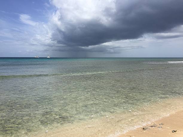 istock Storm Clouds Gather Over a Serene Beach, Creating a Dramatic Contrast Against the Clear Blue Water and Soft Sandy Shore 2248966379