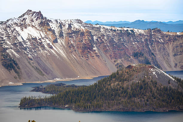 An expansive, wide-angle view of the iconic Wizard Island cinder cone rising from the deep blue waters of Crater Lake National Park in Southern Oregon