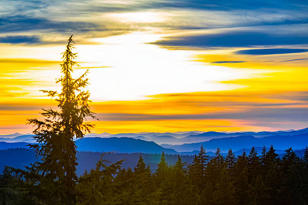 An expansive panoramic view of majestic mountain ranges across Oregon, bathed in the vibrant, colorful hues of a dramatic sunset sky