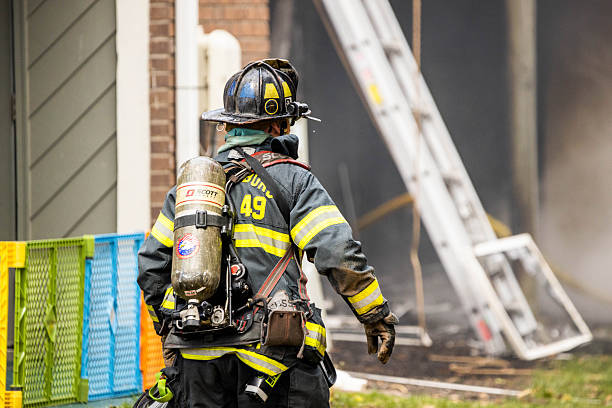 Plainsboro, NJ, USA - March 28, 2022: Close-up view of a firefighter in full protective gear (turnout coat, helmet, breathing apparatus) actively working at the scene of a fire