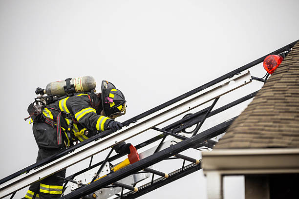Plainsboro, NJ, USA - March 28, 2022: Close-up view of a firefighter in full protective gear (turnout coat, helmet, breathing apparatus) actively working at the scene of a fire