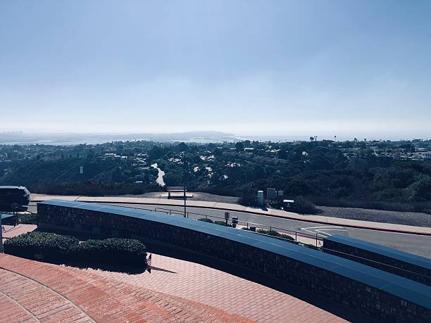 A serene landscape unfolds with rolling hills and a sparkling coastline under a blue sky. Soft sunlight illuminates the scene, enhancing the beauty of nature at midday.