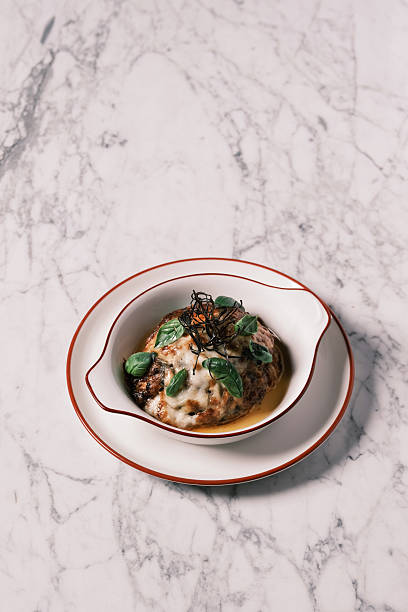 High angle view of Melanzane alla Parmigiana baked with melted cheese and fresh basil leaves, Traditional Southern Italian eggplant dish from Naples, Gourmet comfort food concept for restaurant menu and culinary presentation