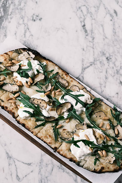 View of truffle pizzetta topped with burrata, arugula, black truffle slices and pine nuts, Modern Italian flatbread from contemporary restaurant cuisine, Gourmet food concept for menu design and culinary branding