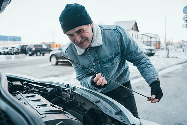 istock Man checking low or dirty engine oil in a car during winter, noticing problems and preparing for oil change and vehicle maintenance 2248980520