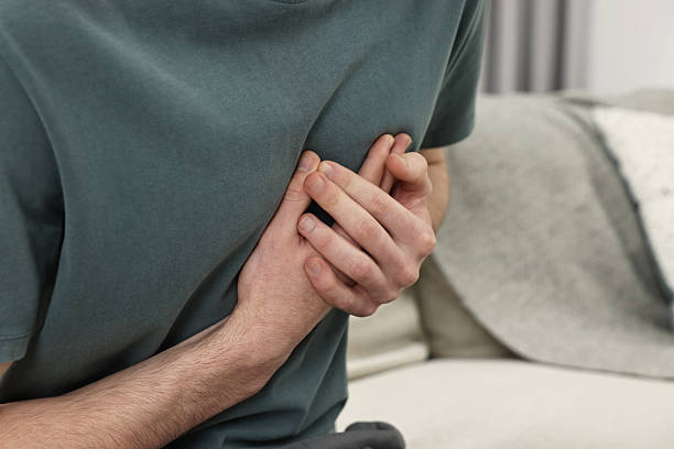 istock Man suffering from heart hurt on sofa at home, closeup 2248980584