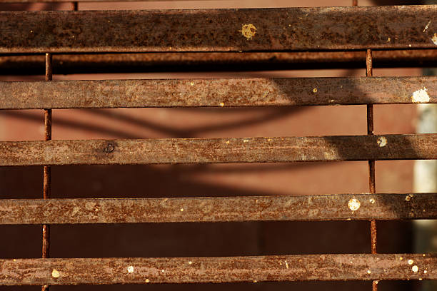 rusty iron brown slats on the back of a seat in sunlight and shadow