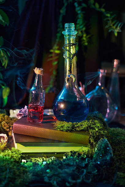 istock Two glass bottles, one filled with red liquid and the other with blue, rest on moss-covered books. environment is dark, with hints of greenery and smoke, enhancing a magical atmosphere 2248987891