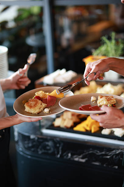 istock Close-up view of guests serving assorted breakfast items onto ceramic plates at an open buffet table, Warm restaurant setting with diverse cheese and pastry selections, Concept for hospitality, brunch service and food presentation 2248988634