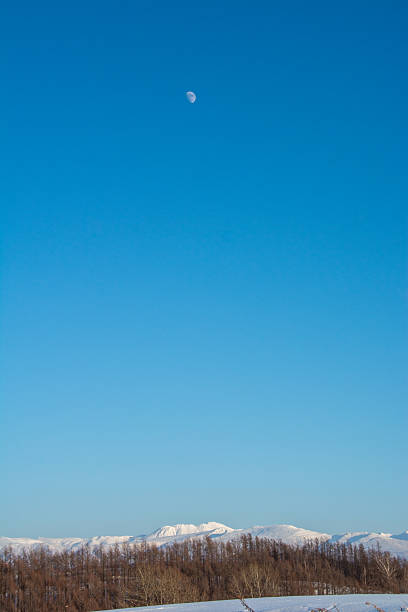Mountains and a crescent moon on a clear winter day