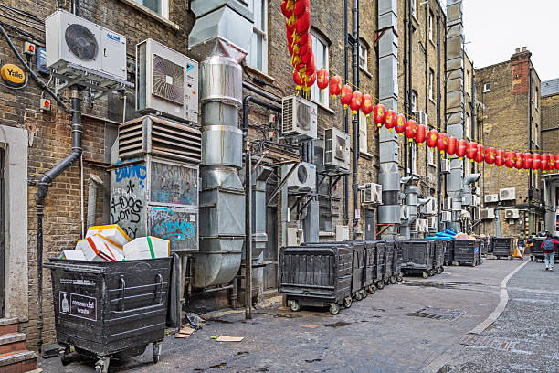 Chinatown, London, England, United Kingdom ,Europe - November 16th 2025: Urban backyard scene in London’s classic Chinatown, showing waste containers and air conditioning units. While the district has transformed in recent years into a fashionable area with popular restaurants, some hidden courtyards still evoke memories of its rough past.