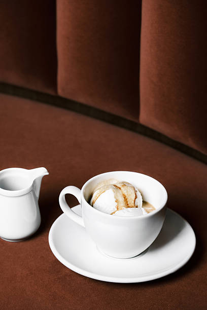 Top view of an affogato dessert with vanilla ice cream served in a white cup alongside a small pitcher of espresso in an Italian restaurant setting, Minimalist coffee dessert presentation for gourmet menu and refined dining visuals