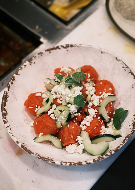 Top view of fresh tomato salad with cucumber slices, crumbled white cheese and mint leaves in a rustic ceramic bowl, Mediterranean appetizer and light meal concept for menu design and culinary projects