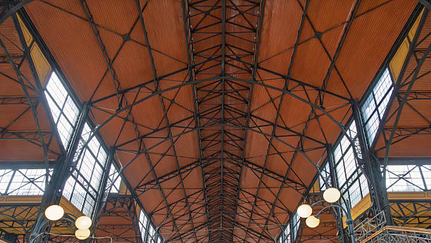 istock Budapest, Hungary - April 2025 Iron and wood ceiling structure with exposed beams and arched windows in Budapest's historic market hall 2248995547