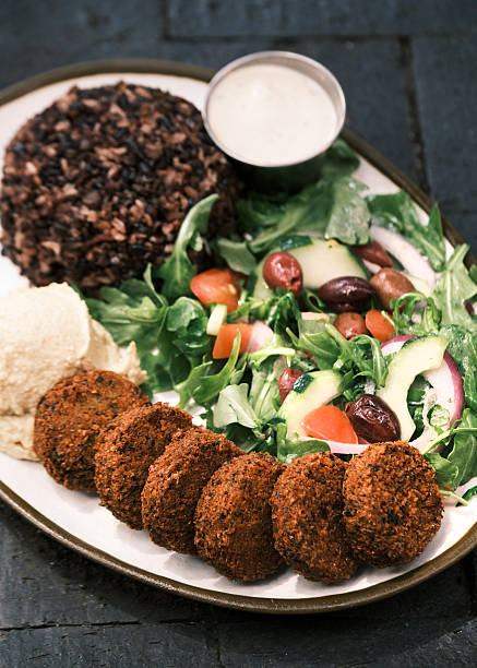 Close-up view of a Mediterranean falafel plate with mixed salad, hummus, wild rice and tahini sauce, Plant-based Middle Eastern meal concept for restaurant menu design and culinary culture visuals