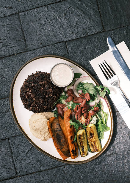 Top view of a Mediterranean-inspired vegetarian plate with black rice, grilled vegetables, hummus and mixed salad, Balanced plant-based meal concept for modern dining visuals and menu design projects