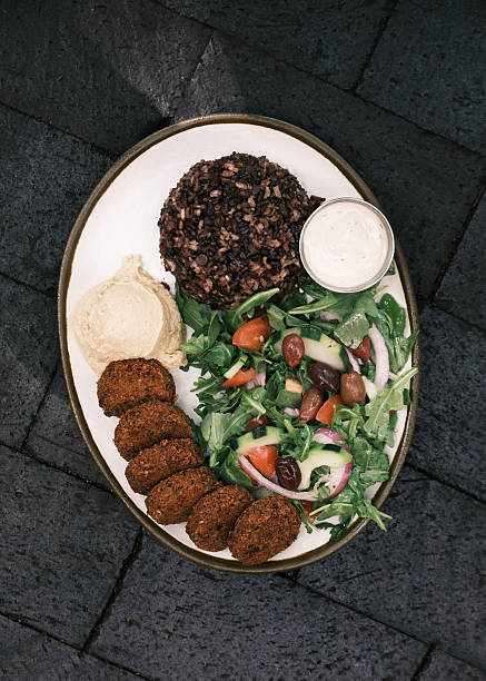 Close-up view of a Mediterranean falafel plate with mixed salad, hummus, wild rice and tahini sauce, Plant-based Middle Eastern meal concept for restaurant menu design and culinary culture visuals