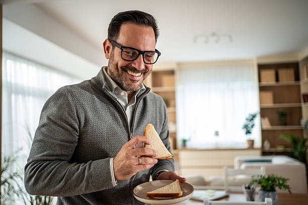 istock Happy man enjoying sandwich for breakfast at home 2248998681