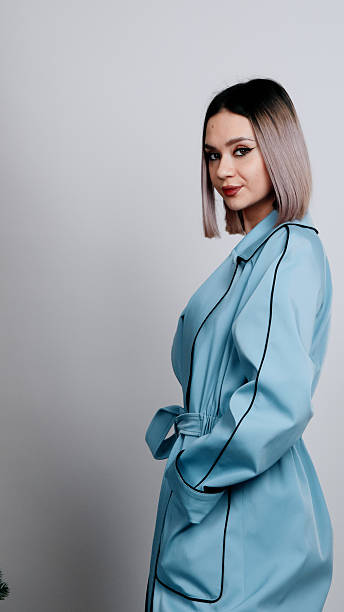 Woman is looking back over her shoulder while wearing a light blue coat