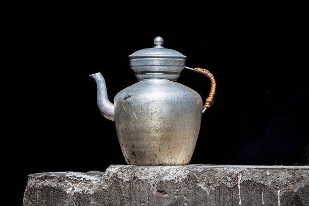 Old handmade tibetan kettle on black background, close up. India, Ladakh