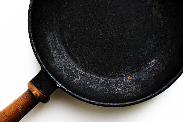 istock Partial overhead view of a seasoned cast-iron pan with wooden handle on a light surface. Rustic kitchenware background 2249007068