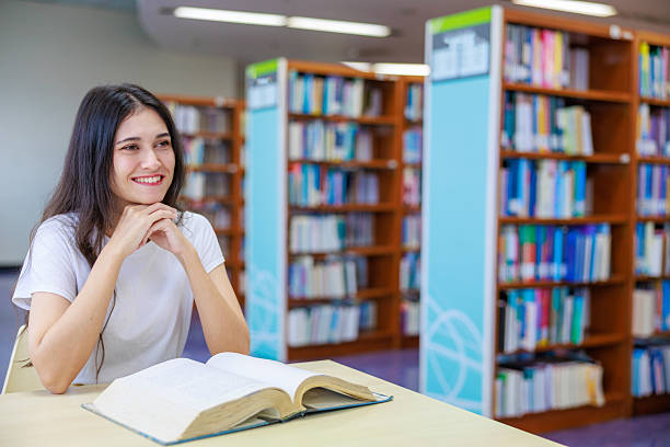 Caucasian female student reading a book alone in a quiet library, capturing education, concentration, and academic lifestyle. Ideal for themes about studying, learning environments, school marketing, and personal development.