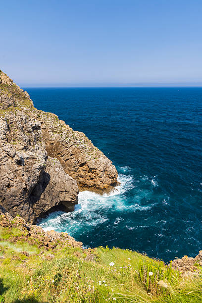 Deep blue sea water meeting rocky cliffs on a sunny day in Cantabria