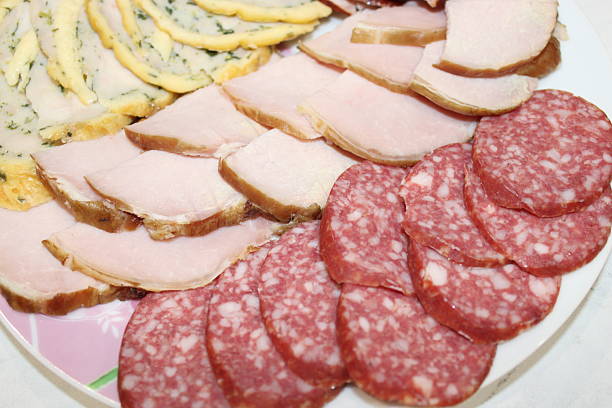 A colorful assortment of cold cuts, including ham, salami, and other meats, is artfully arranged on a round platter. This display is perfect for a party or casual gathering.