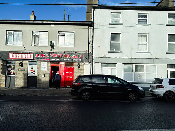 Castlerea, Ireland - October 21, 2025: Hells Kitchen bar and restaurant in Ireland with a bright red door and customers at the entrance.