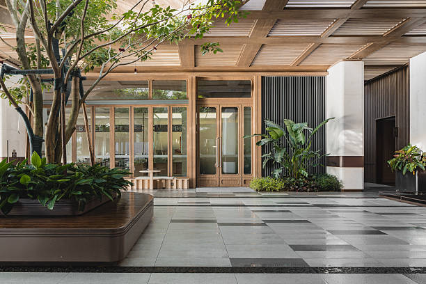 istock Modern building entrance hall featuring large green tree in planter box, polished tiled floor and wooden frame glass doors in background. 2249016092