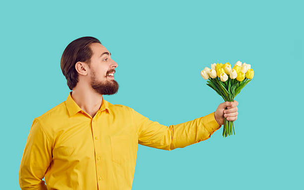 istock Smiling man greeting presenting flowers bouquet 2249016283
