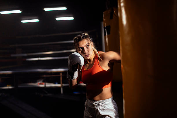 istock Female boxer trains in gym, hitting bag 2249017033