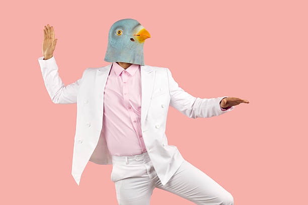 istock Funny man in rubber pigeon mask and in white formal suit dancing on pink background. 2249021069